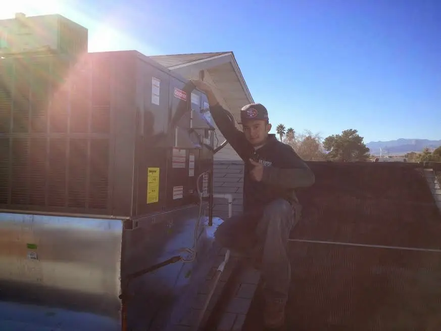 HVAC technician performing Air Duct Repair on a rooftop unit in Halfway